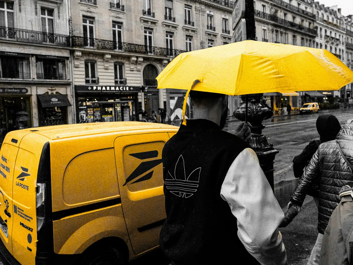 Camionnette jaune de La Poste dans une rue de Paris sous la pluie