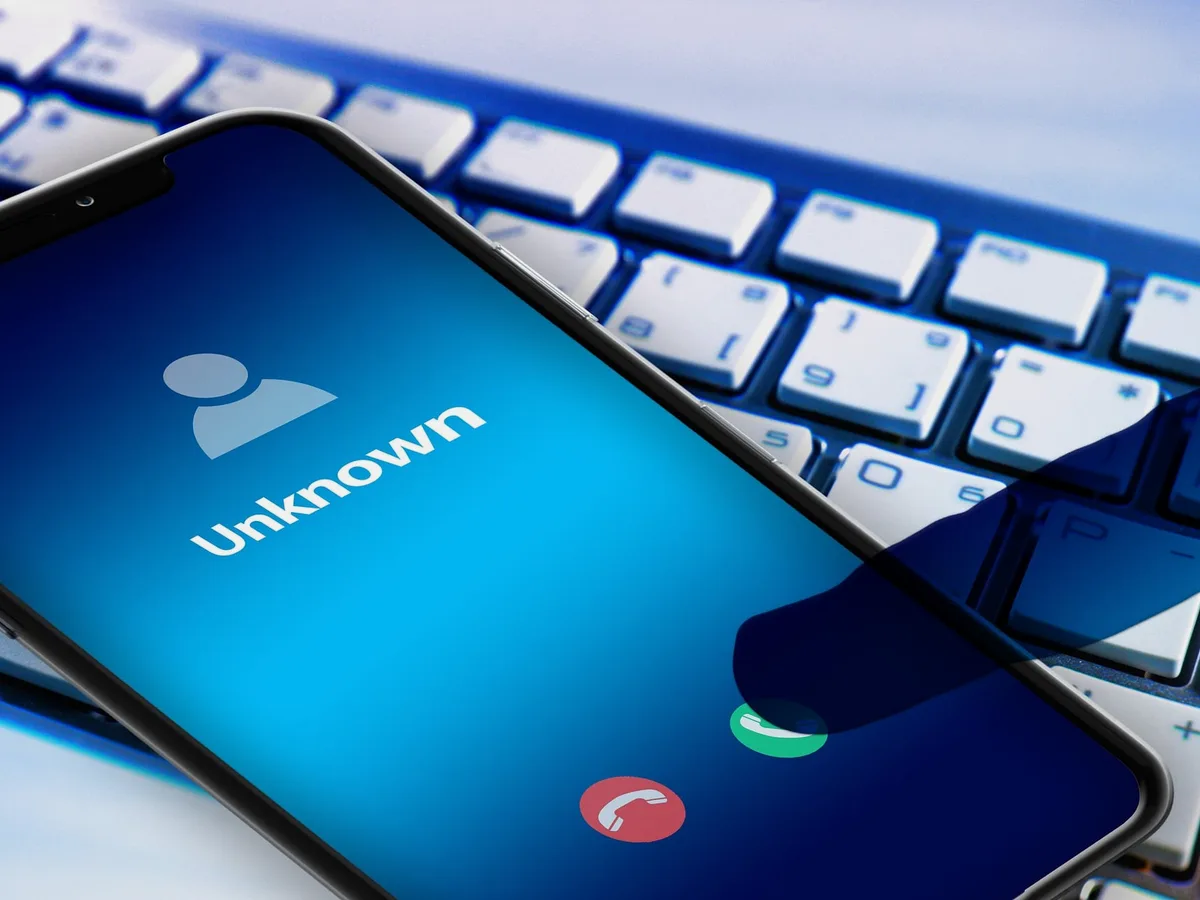 Smartphone affichant un appel d'un numéro inconnu, posé sur un clavier