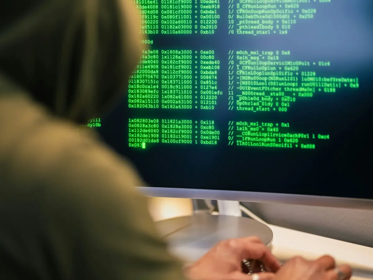 Personne à capuche tapant devant un écran de code