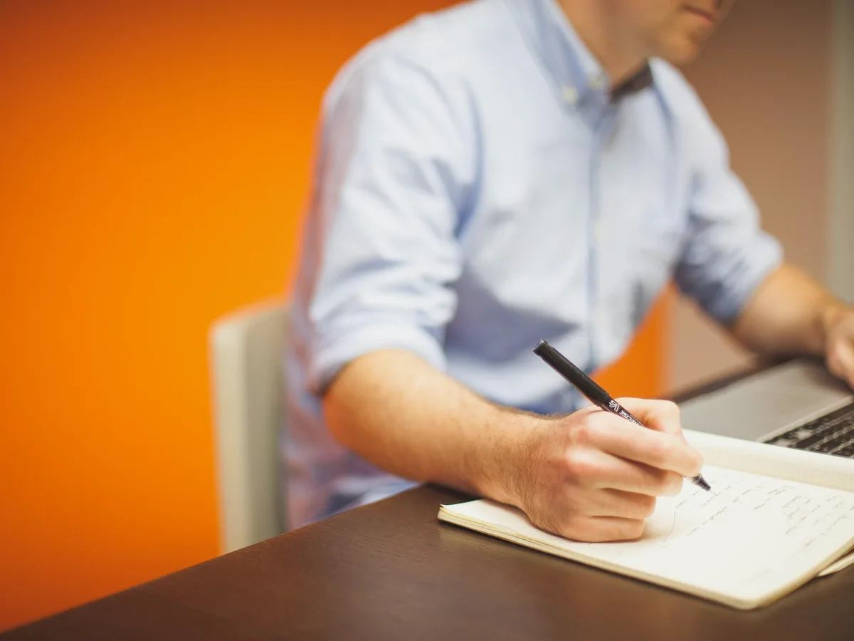 Homme écrivant dans un carnet à son bureau