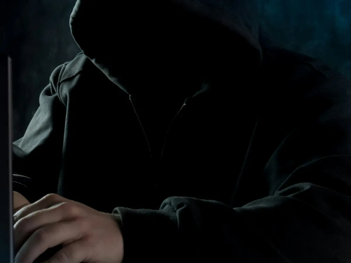 Personne à capuche devant un ordinateur portable