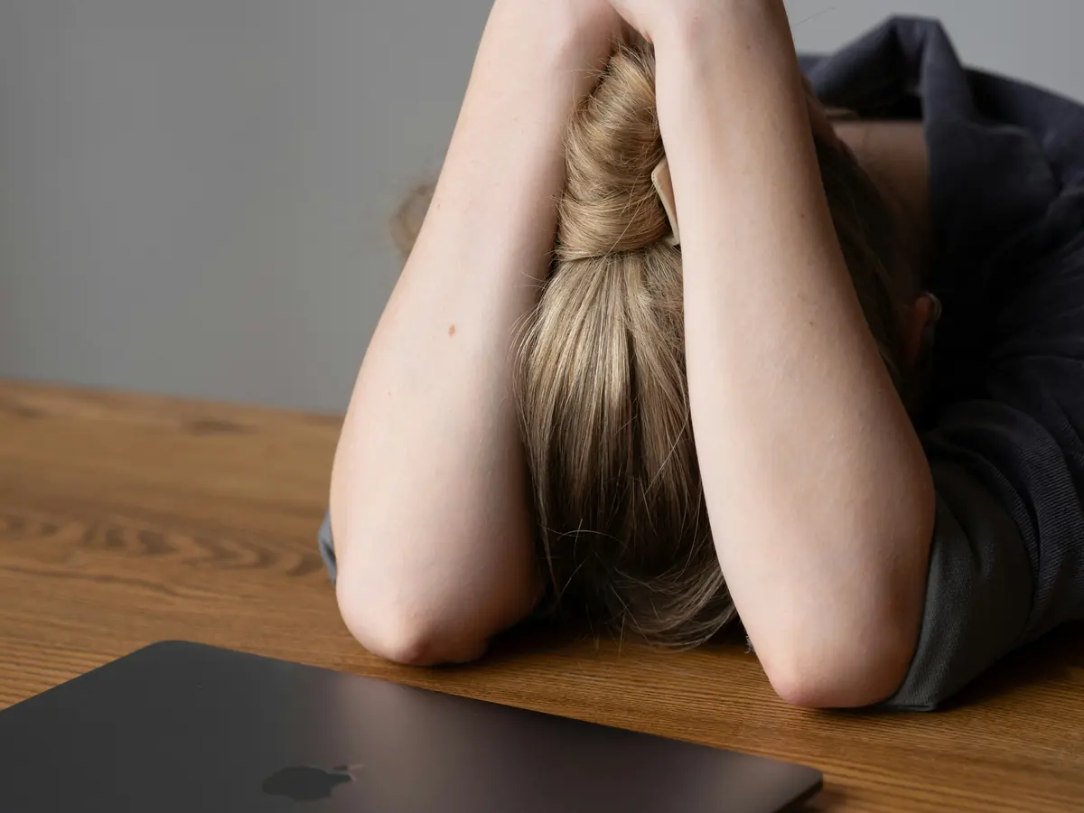 Personne la tête dans les bras devant son ordinateur portable