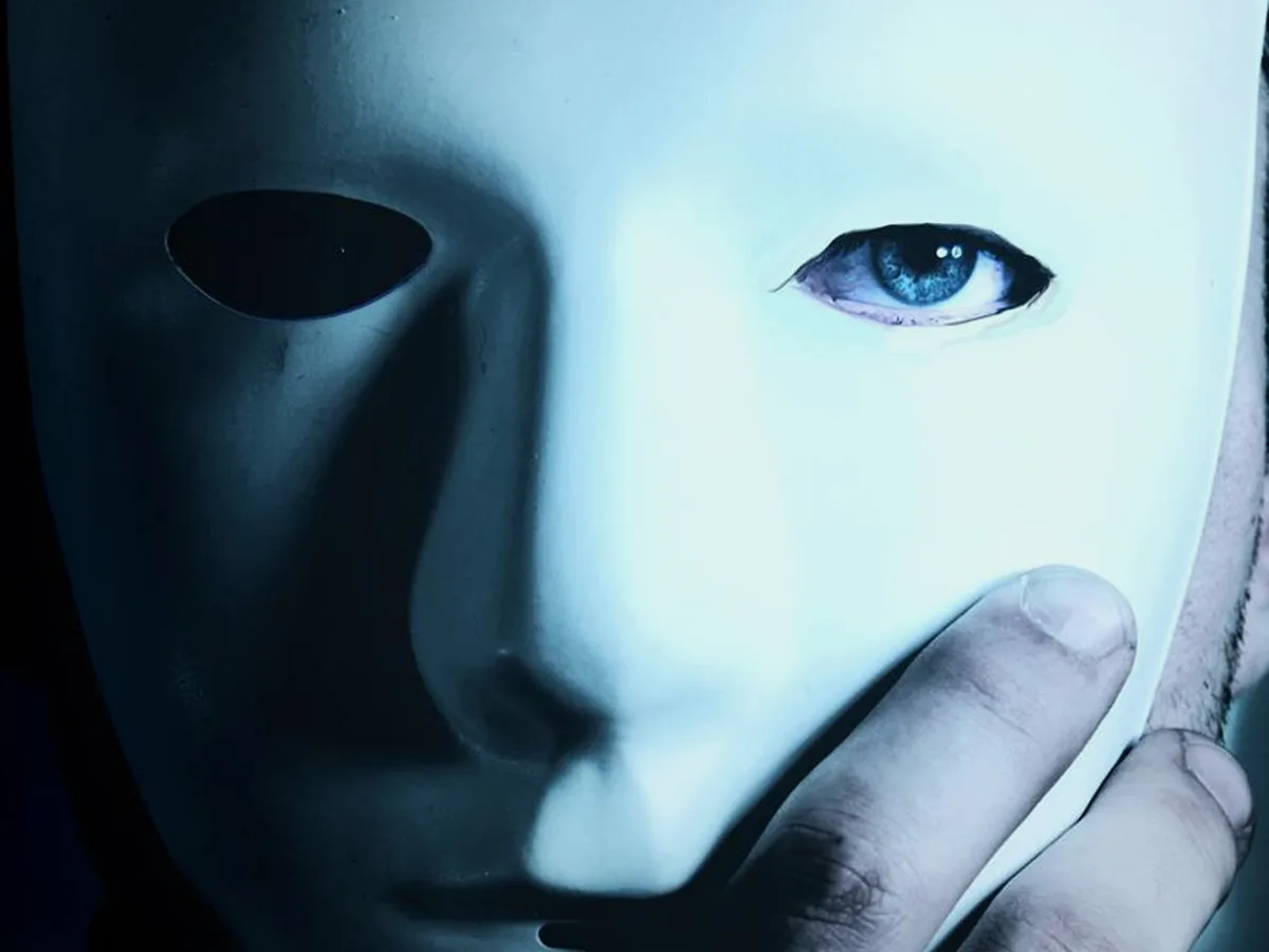 Personne tenant un masque blanc devant son visage