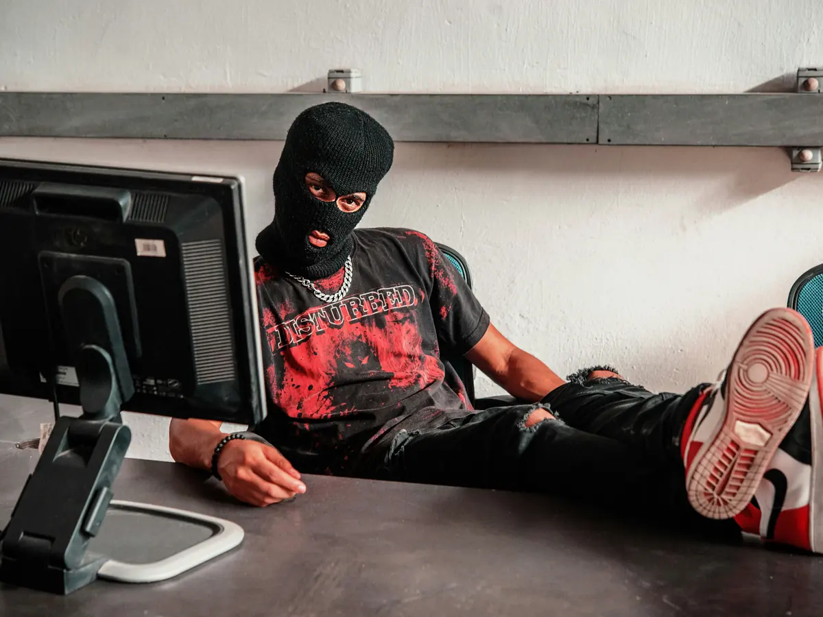 Homme masqué installé à un bureau devant un ordinateur
