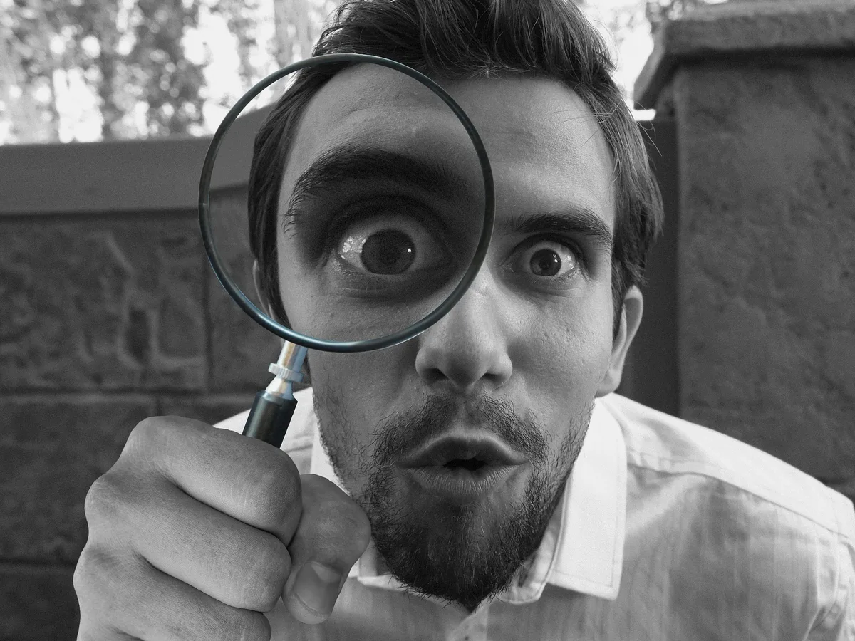 Homme regardant à travers une loupe